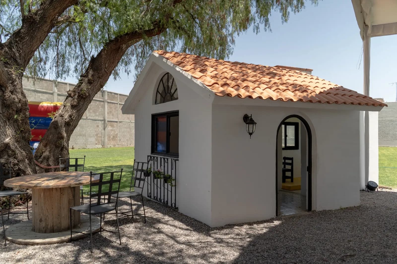 Casita blanca con techo de teja junto al jardín