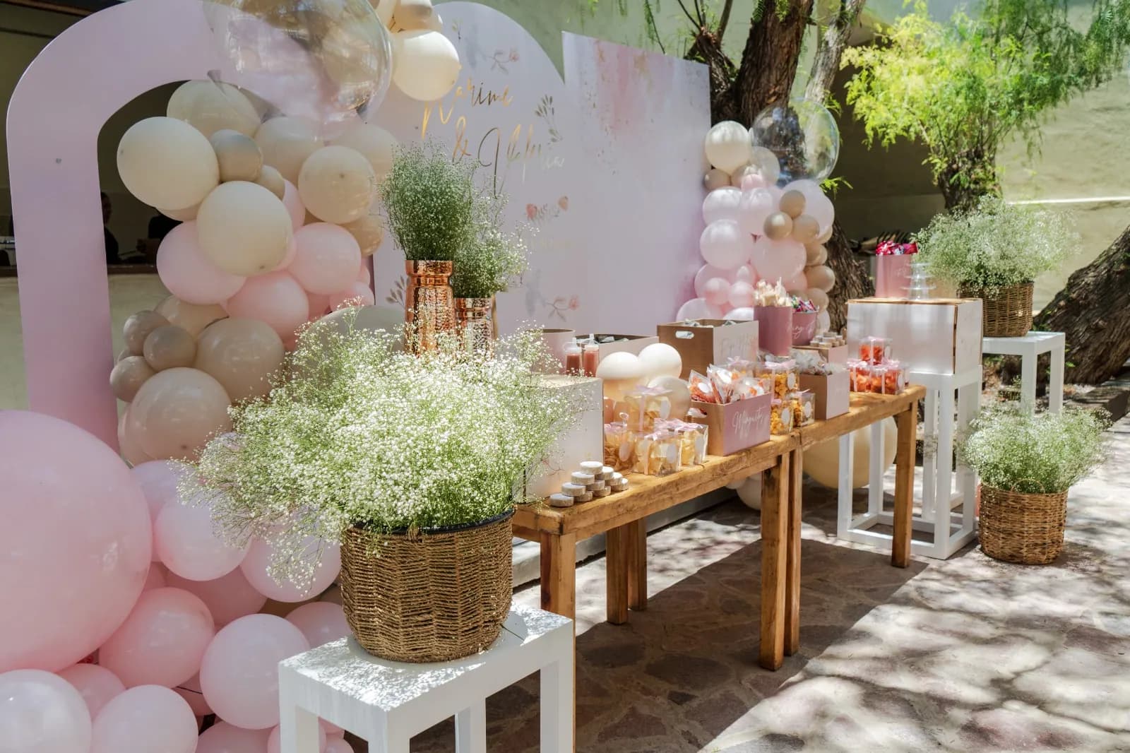 Mesa de postres con globos rosas en el jardín