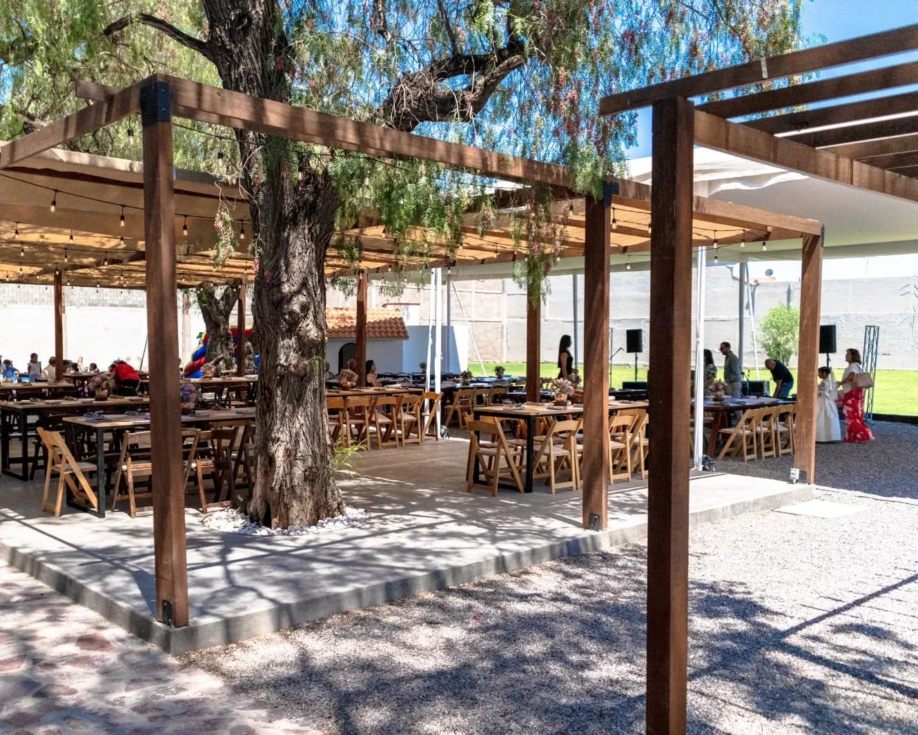 Pérgola de madera con mesas montadas bajo los árboles del Jardín Casilda