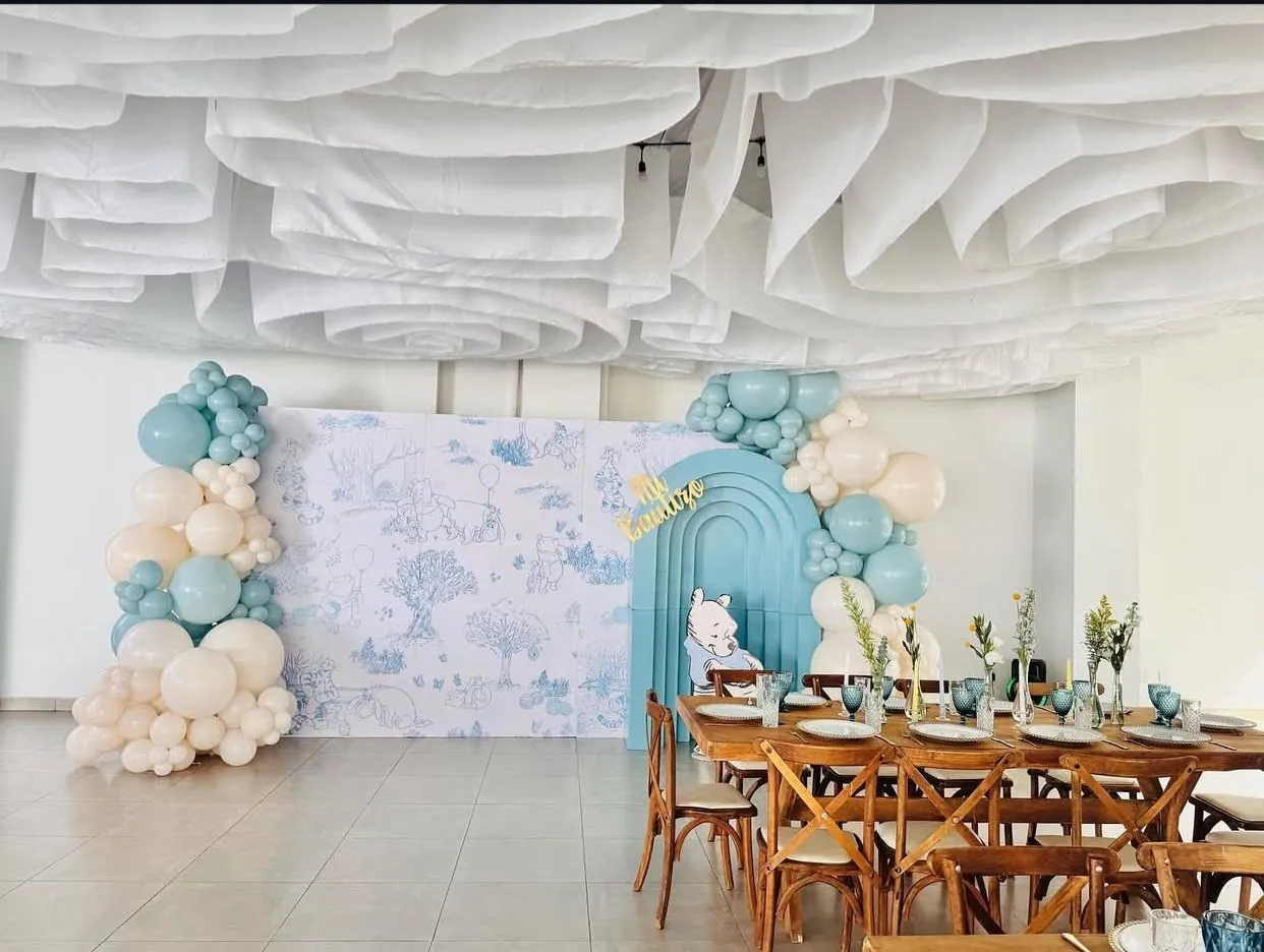 Mesa de bautizo con globos azules y arco decorativo