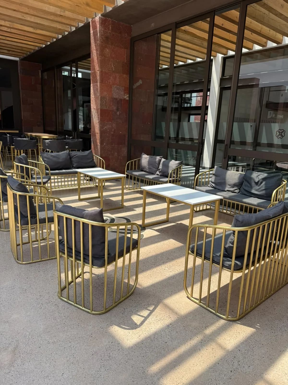Salas lounge doradas con cojines grises en una terraza